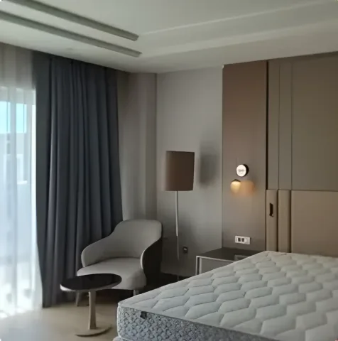 Açık tonlu duvar panelleri ve yatak başlığıyla otel odası